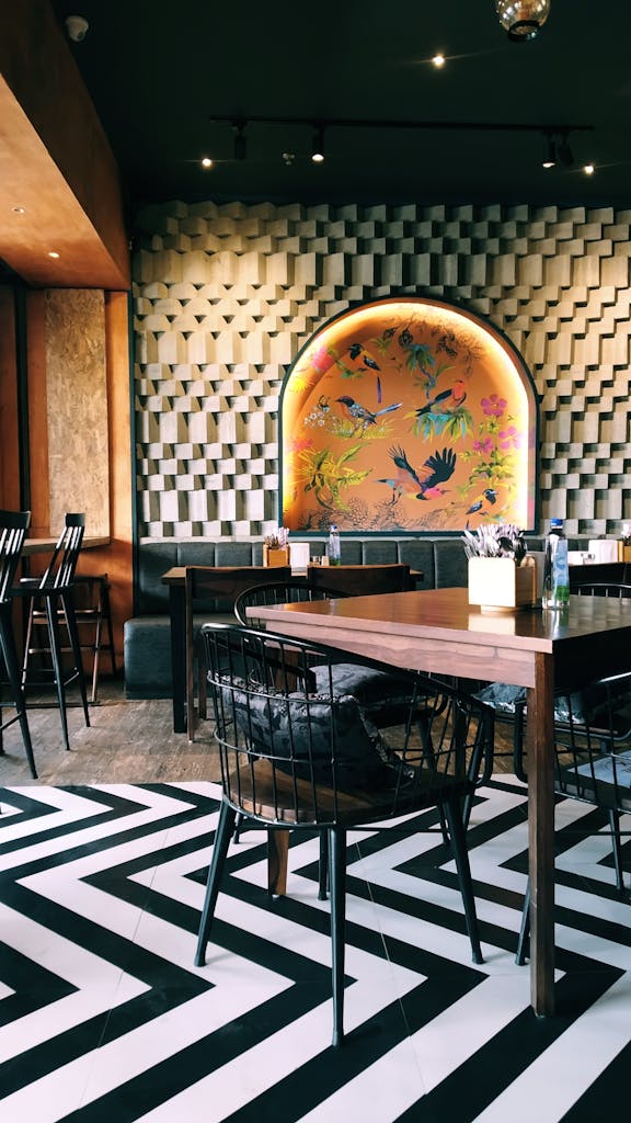 How to increase my restaurant sales?
Chic cafe interior featuring wooden tables, stylish chairs, unique wallpaper, and geometric flooring design.